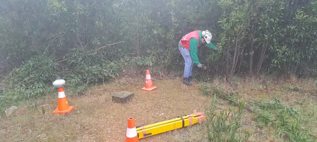 Técnico trabajando junto a un punto de control en terreno con vegetación